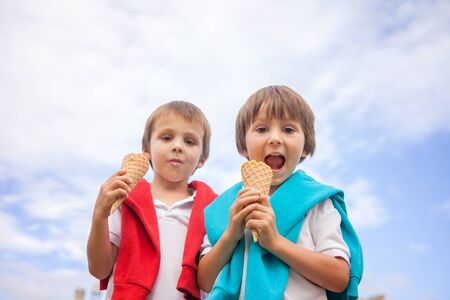 Unusual portrait from below of kids, eating ice cream, looking at camera, smilingの写真素材