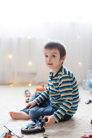 Little child playing with lots of colorful plastic toys indoor, building different cars and objectsの写真素材