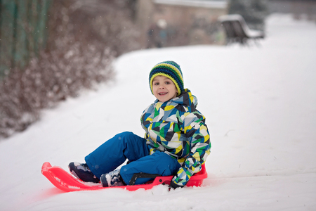 Two kids, boy brothers, sliding with bob in the snow, wintertime, happiness conceptの写真素材