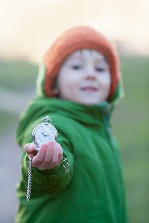Cute preschool boy, holding pocket watch, focus on the watchの写真素材