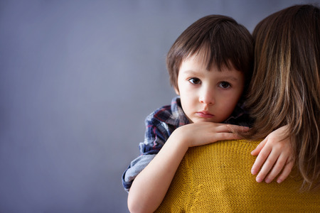 Sad little child, boy, hugging his mother at home, isolated image, copy space. Family conceptの写真素材