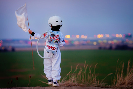 Adorable little boy, dressed as astronaut, playing in the park with rocket and flag, dreaming about becoming an astronautの写真素材