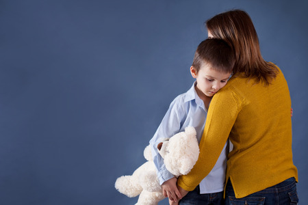Sad little children, boys, hugging their mother at home, isolated image, copy space. Family conceptの写真素材