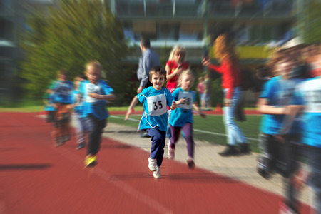 Young preschool children, running on track in a marathon competition, blurred motionの写真素材