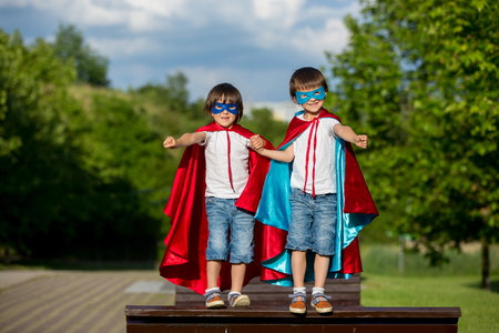 Two sweet little preschool children, boys, playing superhero in the park, summertimeの写真素材