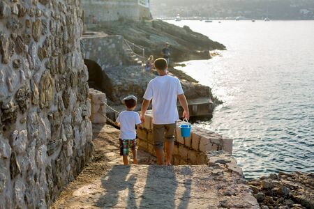 Father and son, walking hand in hand on a sea coast path next to Mediterranean sea in France