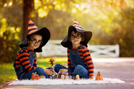 Two children, boy brothers in the park with Halloween costumes, having funの写真素材