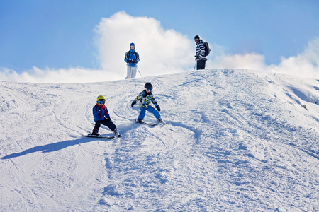 Two young children, siblings brothers, skiing in Austrian mountains on a sunny day, wintertime, enjoying sportsの写真素材