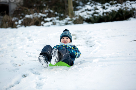 Cute child, boy, sliding with bob in the snow, wintertime, happiness conceptの写真素材