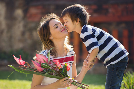 Cute little boy, giving present to his mom for Mothers day in the gardenの写真素材