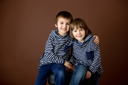 Double portrait of two boys, brothers, isolated on brownの写真素材