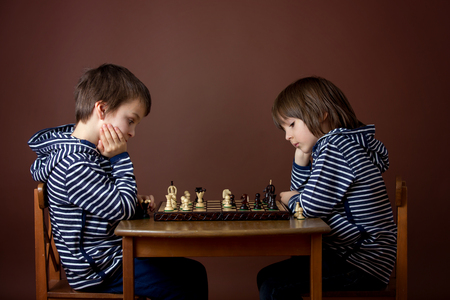 Little boys, playing chess. Smart kid, isolated, playing chess agains his brother. Children playing intelligent gameの写真素材