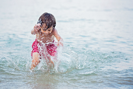 Little cute boy at the beach in the water, swimming and playingの写真素材