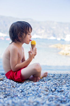Two happy children, boy brothers, eating ice cream on the beach, summertimeの写真素材
