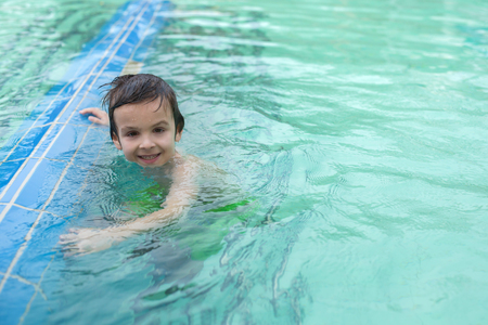 Sweet child, boy, playing in water world playground, enjoying attractions, swimming in a big swimming pool on a holidayの写真素材