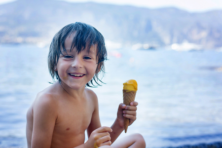Two happy children, boy brothers, eating ice cream on the beach, summertimeの写真素材