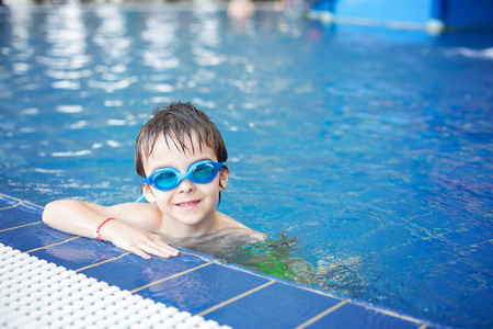 Sweet child, boy, playing in water world playground, enjoying attractions, swimming in a big swimming pool on a holidayの写真素材