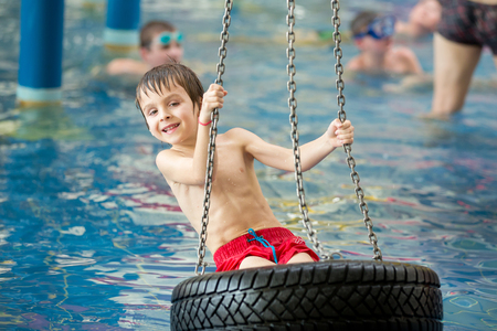 Sweet child, boy, playing in water world playground, enjoying attractions, swimming in a big swimming pool on a holidayの写真素材