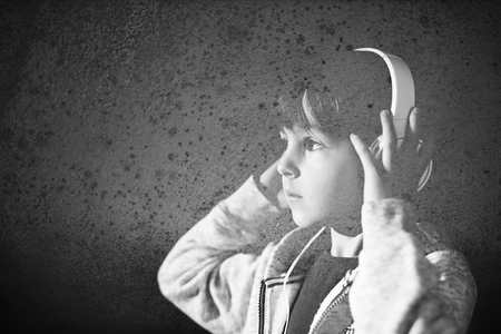 Cute boy with phone and head phones, listening music, indoors, studio shotの写真素材