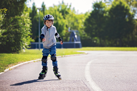 Cute little child, boy, riding on a skating  in the park, springtimeの写真素材