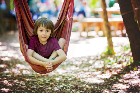 Cheerful child playing and lying inside the hammock, summertimeの写真素材