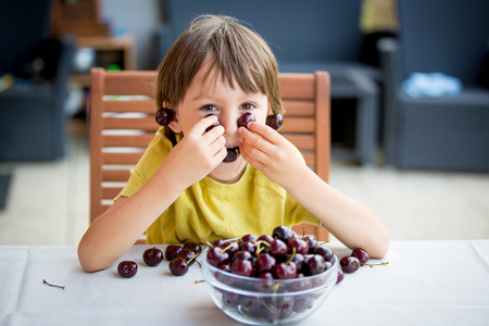 Two sweet children, boy brothers, camping outside summertime on sunset, eating potatoesの写真素材