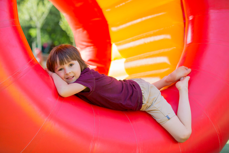 Cute little boy, playing in a rolling plastic cylinder ring with a hole in the middle, outdoorの写真素材