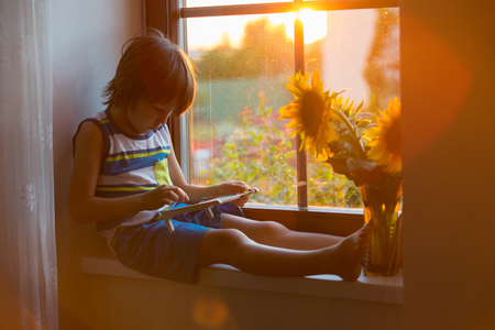 Cute little toddler child, playing with abacus on a window on sunsetの写真素材
