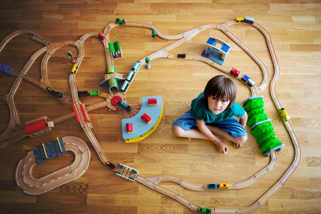 Sweet preschool child, boy, playing with wooden railway and trains at home, top viewの写真素材