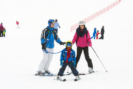Young happy family with one child, skiing in the mountains, wintertimeの写真素材