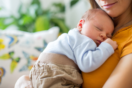 Young mother, holding tenderly her newborn baby boy, close portraitの写真素材