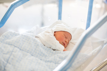Beautiful newborn baby boy, laying in crib in prenatal hospitalの写真素材