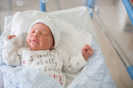 Beautiful newborn baby boy, laying in crib in prenatal hospital