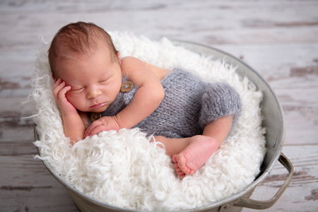 Newborn baby boy, sleeping peacefully in basket, dressed in knitted outfit, chilling out, happy and cuteの写真素材