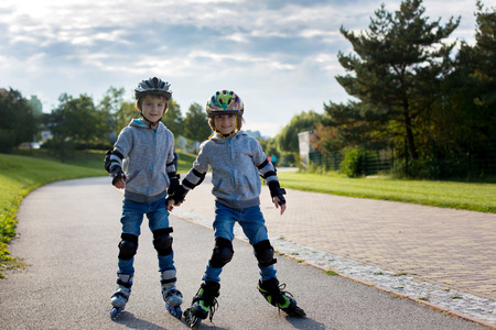 Young preschool cute children, boy brothers, twins, skating in the park, springtimeの写真素材