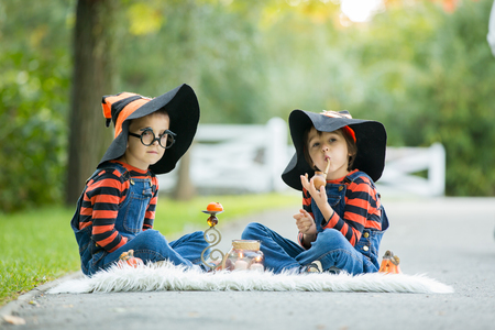 Two children, boy brothers in the park with Halloween costumes, having funの写真素材