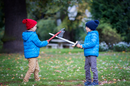 Two boys, playing with swords in the park, autumn timeの写真素材