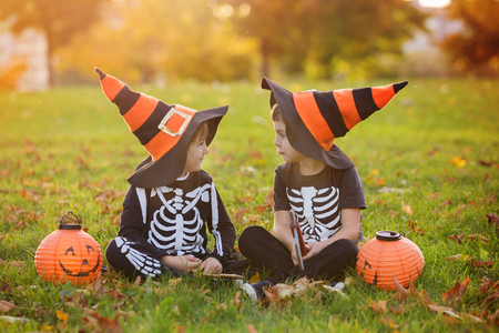 Two children, boy brothers in the park with Halloween costumes, having funの写真素材