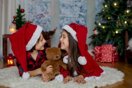 Cute children, boy and girl, having fun on Christmas, xmas decoration around themの写真素材