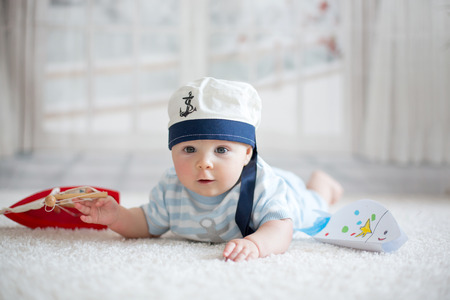 Little baby boy, playing wtih little boat and little fish at home, having sailor hatの写真素材