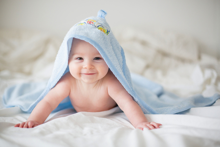 Cute little baby boy, relaxing in bed after bath, smiling happily, daytimeの写真素材