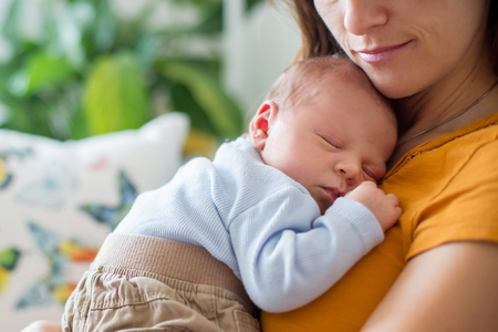 Young mother, holding tenderly her newborn baby boy, close portraitの写真素材