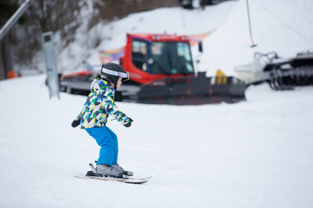 Cute little preschool child in blue jacket, skiing happily on a sunny day in Alpsの写真素材