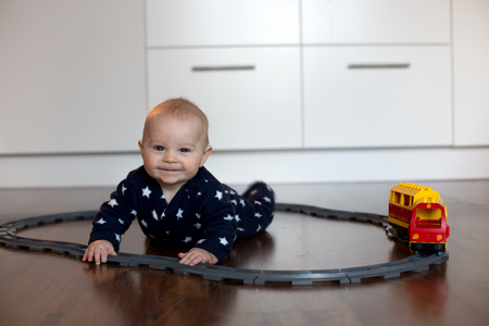Little baby boy, playing with train and railroad at home in living roomの写真素材