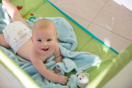 Little cute baby boy, playing with toys in a mobile crib on a sunny day, picture through webの写真素材