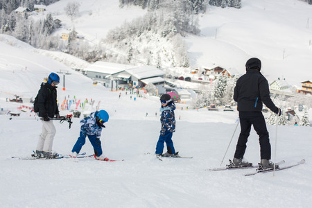 Family skiing together in austrian resort, snowy dayの写真素材