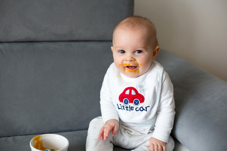 Little baby boy, eating mashed food for the first time in his life