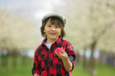 Two children, boy brothers, having fun with easter eggs in the park, beautiful spring blooming...