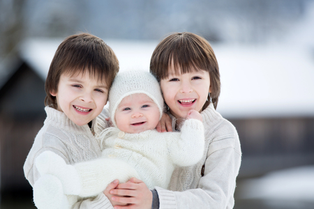 Three beautiful boys, brothers, having portrait on a winter sunny day, snowy landscape の写真素材