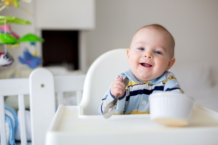 Cute little baby boy, eating mashed vegetables for lunch, mom feeding him, sweet toddler boy, smilingの写真素材
